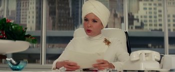 Movie still from “Down with Love” (2003), directed by Peyton Reed – A woman in a turban is sitting at a table with a letter; Close Up shot, Low angle