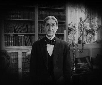 Movie still from “Dr. Jekyll and Mr. Hyde” (1931), directed by Rouben Mamoulian – A man in a suit standing in front of bookshelves; Medium shot, Low angle