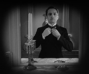 Movie still from “Dr. Jekyll and Mr. Hyde” (1931), directed by Rouben Mamoulian – A black and white photo of a man in a suit and bow tie in front of a mirror; Medium shot, Low angle