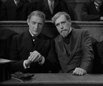 Movie still from “Dr. Jekyll and Mr. Hyde” (1931), directed by Rouben Mamoulian – A couple of men sitting next to each other in a courtroom; Medium shot, Low angle