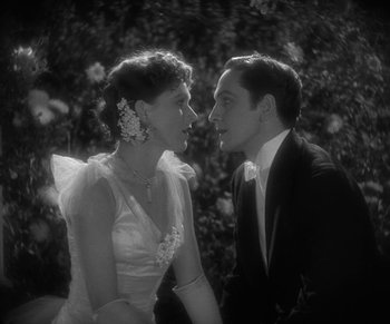 Movie still from “Dr. Jekyll and Mr. Hyde” (1931), directed by Rouben Mamoulian – A man and a woman in formal wear standing next to each other in front of a bush; Medium shot, High angle
