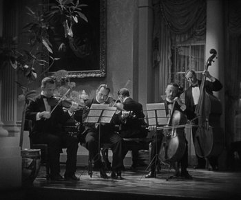 Movie still from “Dr. Jekyll and Mr. Hyde” (1931), directed by Rouben Mamoulian – A black and white photo of a group of men playing instruments; Wide shot, High angle