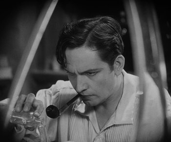 Movie still from “Dr. Jekyll and Mr. Hyde” (1931), directed by Rouben Mamoulian – A black - and - white photo of a man smoking a pipe; Close Up shot, High angle