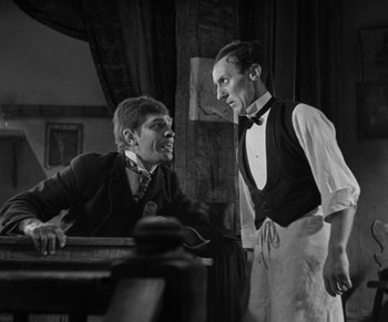 Movie still from “Dr. Jekyll and Mr. Hyde” (1931), directed by Rouben Mamoulian – A man and a boy talking to each other in front of a table; Medium shot, Low angle