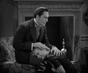 Movie still from “Dr. Jekyll and Mr. Hyde” (1931), directed by Rouben Mamoulian – A man and a woman sitting on a couch in front of a fire place; Medium shot, High angle