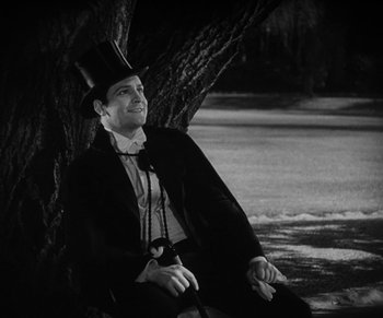 Movie still from “Dr. Jekyll and Mr. Hyde” (1931), directed by Rouben Mamoulian – A man in a top hat sitting next to a tree; Medium shot, Low angle
