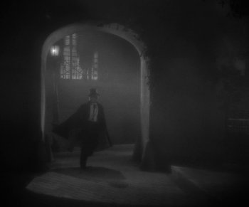 Movie still from “Dr. Jekyll and Mr. Hyde” (1931), directed by Rouben Mamoulian – A man wearing a top hat walking through a dark room; Wide shot, Low angle