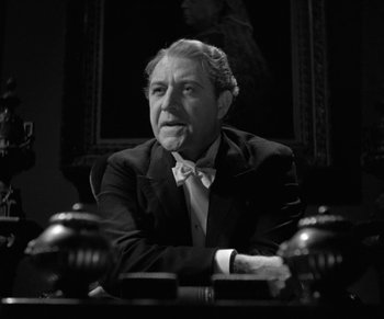 Movie still from “Dr. Jekyll and Mr. Hyde” (1931), directed by Rouben Mamoulian – An older man sitting at a desk in front of a painting; Medium shot, Low angle