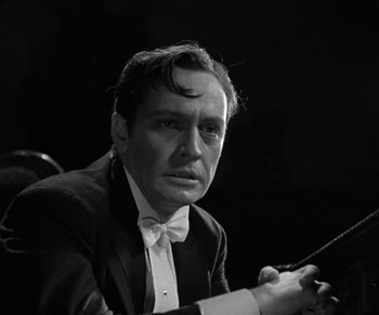 Movie still from “Dr. Jekyll and Mr. Hyde” (1931), directed by Rouben Mamoulian – A black and white photo of a man in a suit holding a conductor's baton; Close Up shot, Low angle