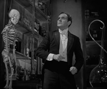 Movie still from “Dr. Jekyll and Mr. Hyde” (1931), directed by Rouben Mamoulian – A man in a suit standing next to a skeleton in a room; Medium shot, Low angle