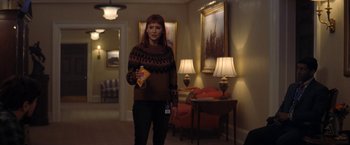 Movie still from “Don't Look Up” (2021), directed by Adam McKay – A woman standing in a living room holding a bag of chips; Medium shot, Over the shoulder angle