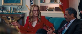 Movie still from “Don't Look Up” (2021), directed by Adam McKay – A woman sitting on a couch wearing a red jacket; Medium shot, Over the shoulder angle