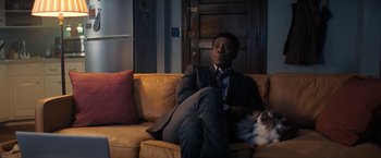 Movie still from “Don't Look Up” (2021), directed by Adam McKay – A man sitting on top of a brown couch next to a cat; Medium shot, Over the shoulder angle