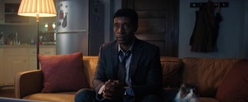 Movie still from “Don't Look Up” (2021), directed by Adam McKay – A man in a suit sitting on a couch in a living room; Medium shot, Over the shoulder angle