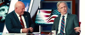 Movie still from “Don't Look Up” (2021), directed by Adam McKay – Two men sitting in front of an american flag on a television screen; Medium shot, Over the shoulder angle