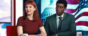 Movie still from “Don't Look Up” (2021), directed by Adam McKay – A woman and a man sitting next to each other in front of an image of the u; Medium shot, Over the shoulder angle