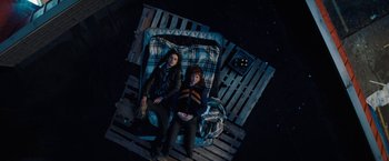 Movie still from “Don't Look Up” (2021), directed by Adam McKay – Two women are laying on a bed in a dark room; Wide shot, Overhead angle