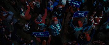Movie still from “Don't Look Up” (2021), directed by Adam McKay – A group of people standing around each other holding political signs; Medium shot, High angle
