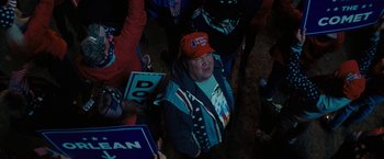Movie still from “Don't Look Up” (2021), directed by Adam McKay – A woman wearing an orange hat sitting on the ground; Medium shot, High angle