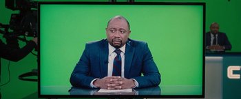 Movie still from “Don't Look Up” (2021), directed by Adam McKay – A man sitting at a desk in front of a green screen; Medium shot, Over the shoulder angle