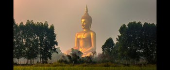 Movie still from “Don't Look Up” (2021), directed by Adam McKay – A large golden buddha statue sitting in the middle of a field; Extreme Wide shot, Low angle