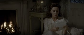 Movie still from “Dracula” (1979), directed by John Badham – A woman sitting in front of a table holding a candle; Medium shot, High angle