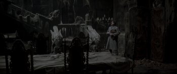 Movie still from “Dracula” (1979), directed by John Badham – A man standing in front of a chair in a dark room; Wide shot, High angle