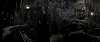 Movie still from “Dracula” (1979), directed by John Badham – A man dressed as a vampire standing in a dark room; Wide shot, Low angle