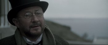Movie still from “Dracula” (1979), directed by John Badham – An old man wearing glasses and a hat; Close Up shot, Over the shoulder angle