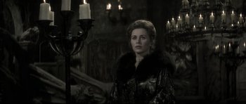 Movie still from “Dracula” (1979), directed by John Badham – A woman standing in front of a candle lit chandelier; Medium shot, Over the shoulder angle