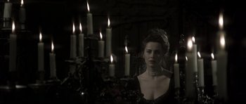 Movie still from “Dracula” (1979), directed by John Badham – A woman in a black dress with candles in the background; Medium shot, Over the shoulder angle