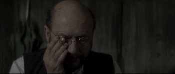 Movie still from “Dracula” (1979), directed by John Badham – A man with a bald head wearing glasses and a suit; Close Up shot, Over the shoulder angle