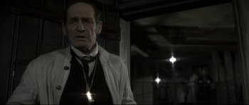 Movie still from “Dracula” (1979), directed by John Badham – An older man wearing a white shirt and a black tie; Close Up shot, Low angle