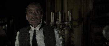 Movie still from “Dracula” (1979), directed by John Badham – A man in a suit and tie standing in front of candles in a room; Close Up shot, Low angle