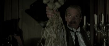 Movie still from “Dracula” (1979), directed by John Badham – A man in a suit and tie holding a bunch of mushrooms; Close Up shot, Low angle