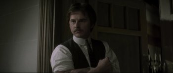 Movie still from “Dracula” (1979), directed by John Badham – A man in a vest and tie standing next to a door; Close Up shot, Low angle