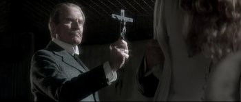 Movie still from “Dracula” (1979), directed by John Badham – An old man holding a crucifixion cross in his hand; Close Up shot, Low angle