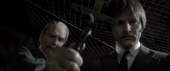 Movie still from “Dracula” (1979), directed by John Badham – A man holding a cross in front of another man in a suit; Close Up shot, High angle