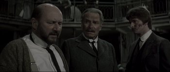 Movie still from “Dracula” (1979), directed by John Badham – Two men standing next to each other wearing suits and ties; Medium shot, Over the shoulder angle