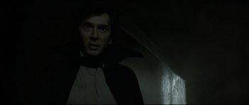 Movie still from “Dracula” (1979), directed by John Badham – A man in a dracula costume standing in the dark; Medium shot, Low angle