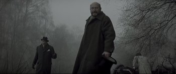 Movie still from “Dracula” (1979), directed by John Badham – A man in a long coat holding a knife in the fog; Medium shot, Low angle