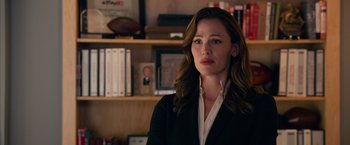 Movie still from “Draft Day” (2014), directed by Ivan Reitman – A woman standing in front of a book shelf; Close Up shot, Over the shoulder angle