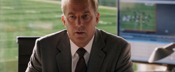 Movie still from “Draft Day” (2014), directed by Ivan Reitman – A person wearing a suit and tie; Close Up shot, Over the shoulder angle