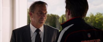 Movie still from “Draft Day” (2014), directed by Ivan Reitman – A man wearing a suit and tie talking to another man; Close Up shot, Over the shoulder angle