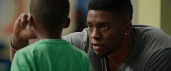 Movie still from “Draft Day” (2014), directed by Ivan Reitman – A young man talking to a young boy; Close Up shot, Over the shoulder angle