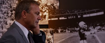 Movie still from “Draft Day” (2014), directed by Ivan Reitman – A person standing in front of a wall; Close Up shot, Over the shoulder angle