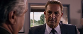 Movie still from “Draft Day” (2014), directed by Ivan Reitman – A person wearing a suit and tie; Close Up shot, Over the shoulder angle