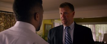 Movie still from “Draft Day” (2014), directed by Ivan Reitman – A man wearing a suit and tie talking to another man; Close Up shot, Over the shoulder angle