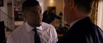 Movie still from “Draft Day” (2014), directed by Ivan Reitman – A man wearing a white dress shirt and a blue tie talking to another man in a suit; Close Up shot, Over the shoulder angle