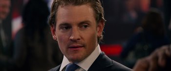 Movie still from “Draft Day” (2014), directed by Ivan Reitman – A person wearing a suit and tie; Close Up shot, Over the shoulder angle